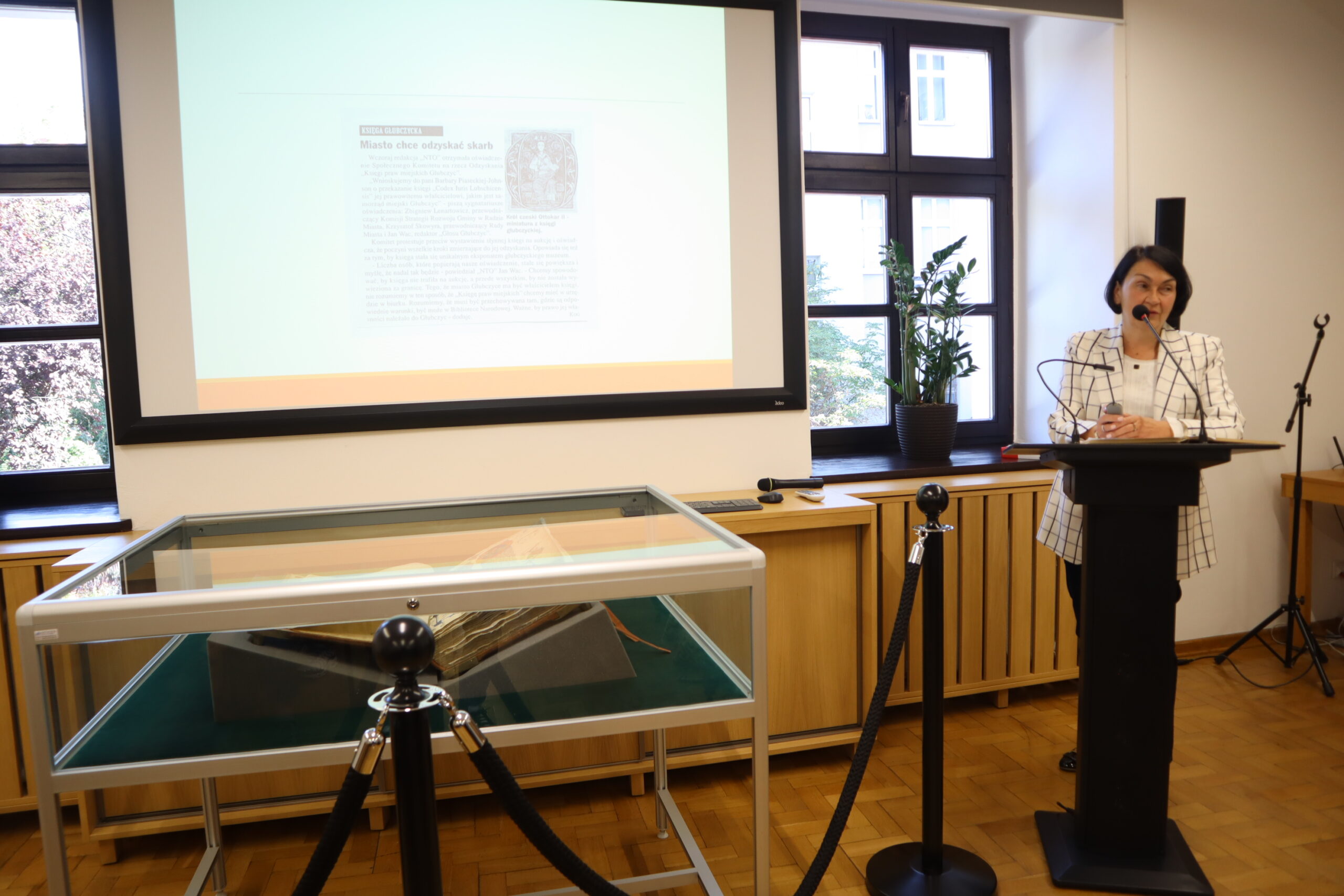 Barbara Sypko prezentuje Księgę głubczycką wystawioną w gablocie